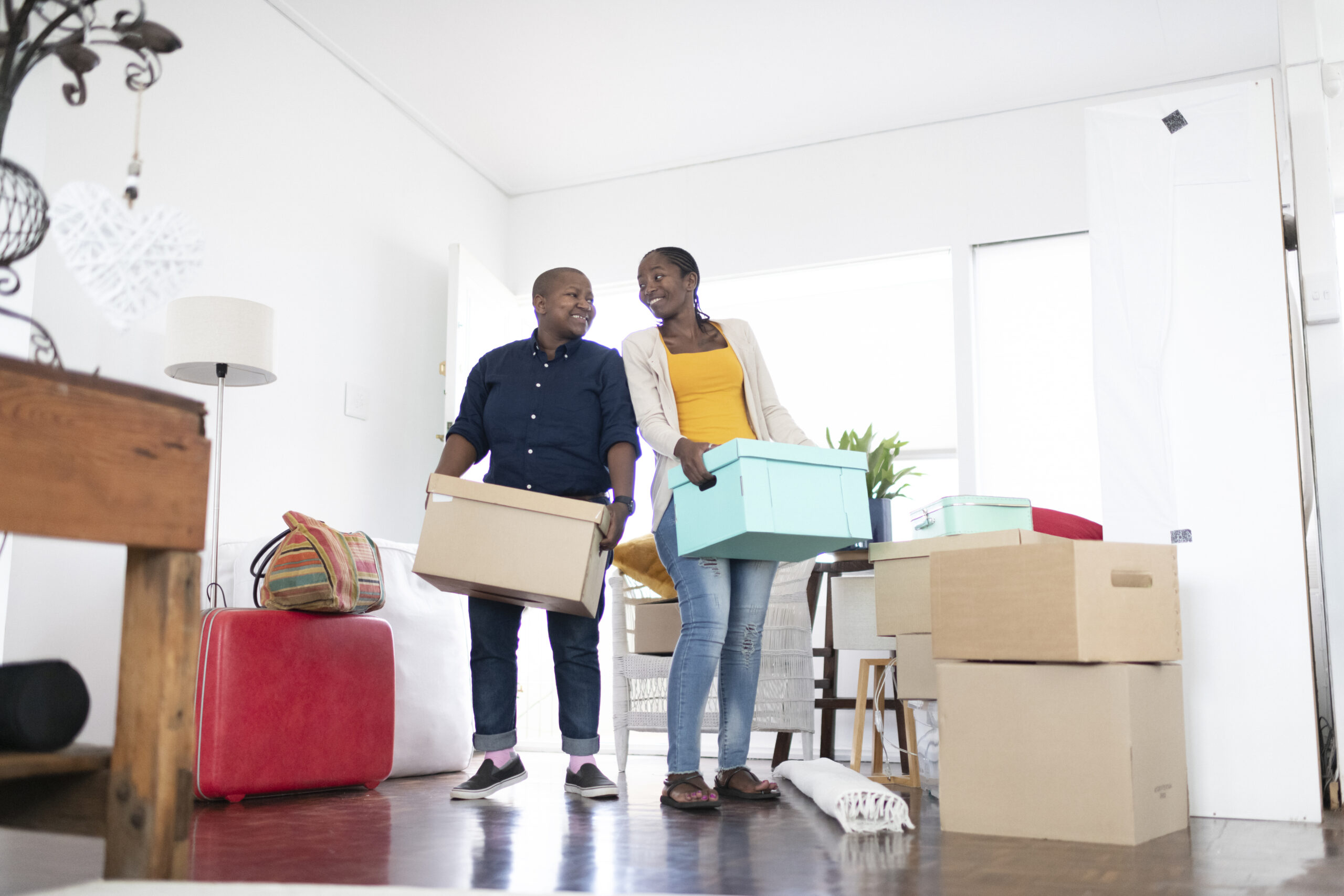 African female couple carry boxes into their new home