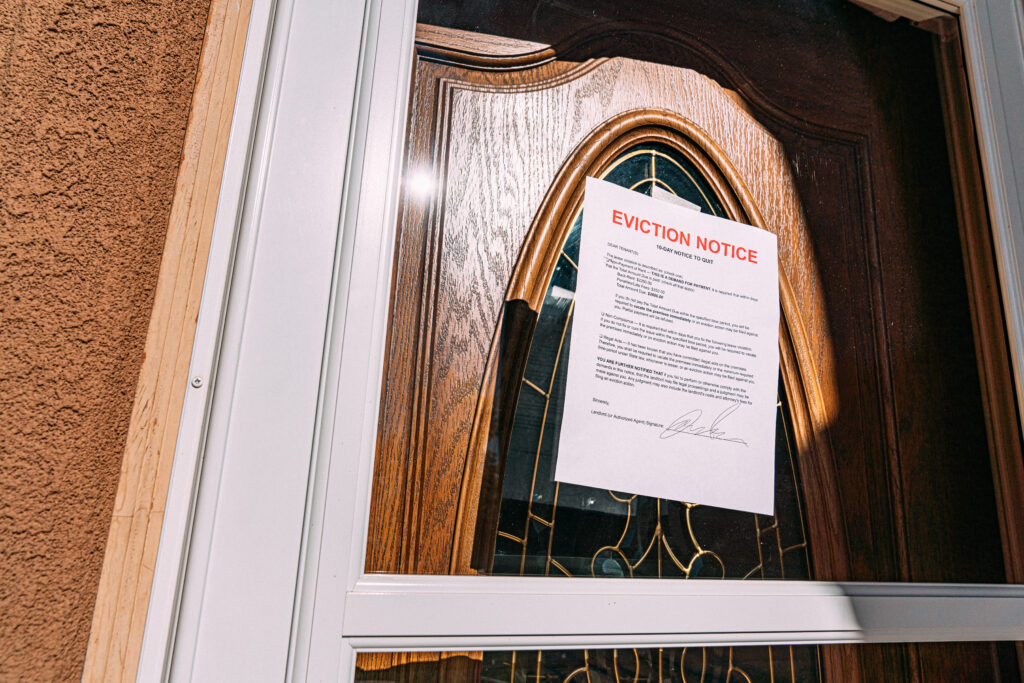 Low Angle Shot of a Paper Eviction Notice Taped to the Glass Front Door of a Rental Home in a Residential Suburban Neighborhood