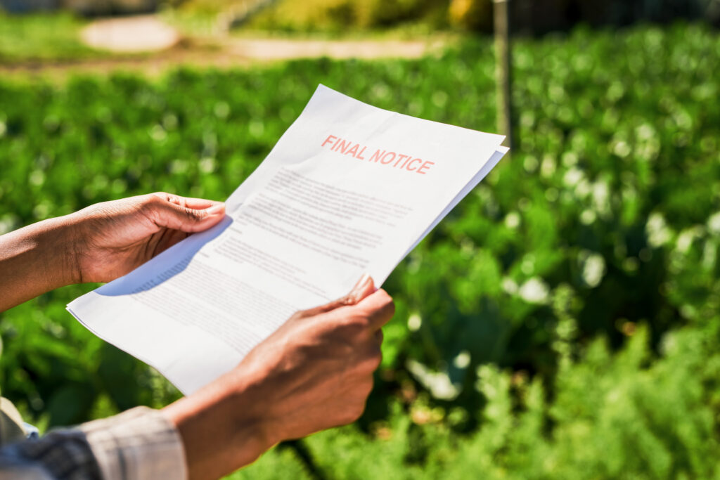 Closeup shot of an unrecognisable woman holding a letter of final notice on a farm