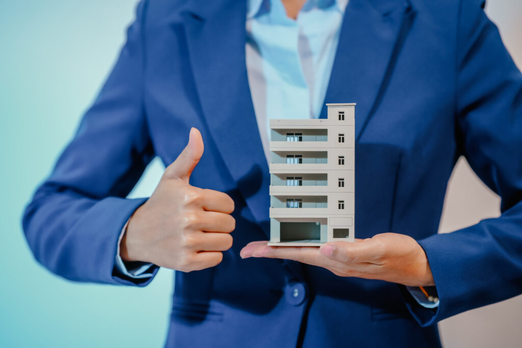 A female employee works at her desk in a real estate office, managing condo sales in the city. She communicates with clients, handles listings, and provides information about available properties