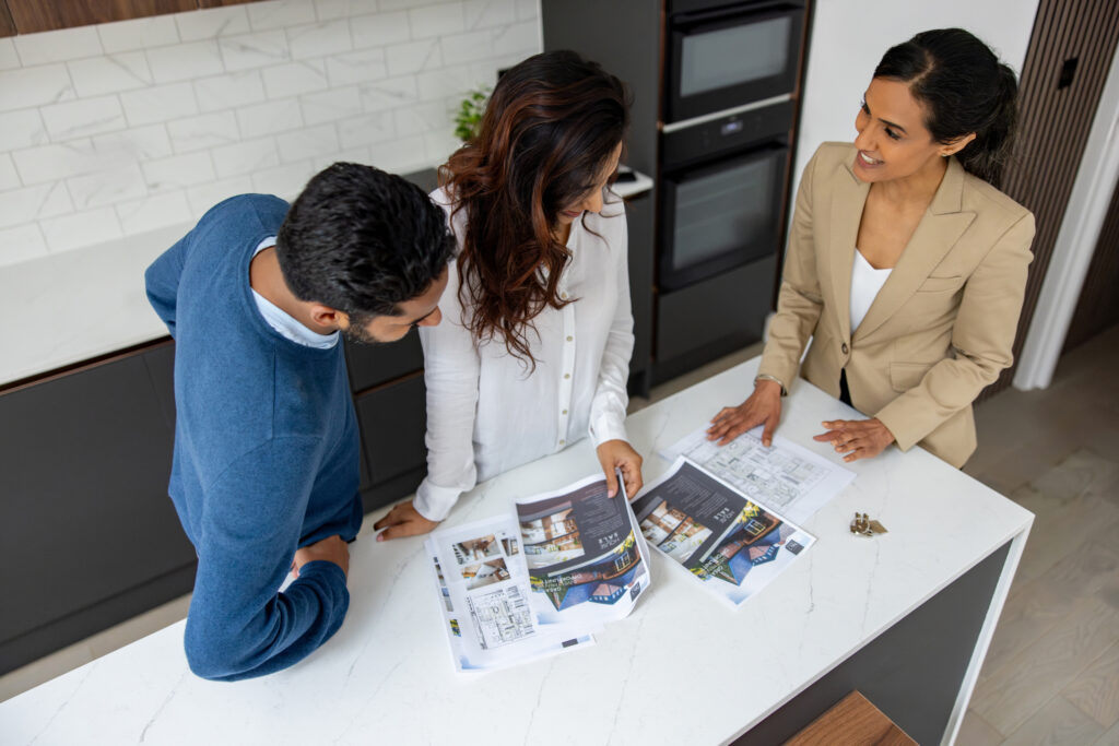 Real estate agent showing brochures of a house for sale to a couple of clients