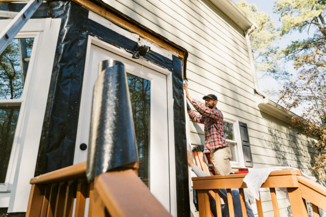 Construction workers repairing the siding of a house