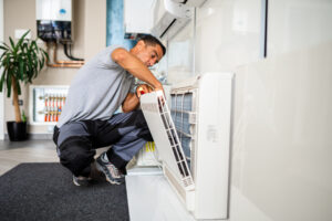 HVAC technician cleaning filter of air conditioning unit.
