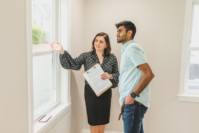a person with a clipboard showing someone a property interior