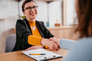 Young woman shaking hands after agreeing to purchase a home.