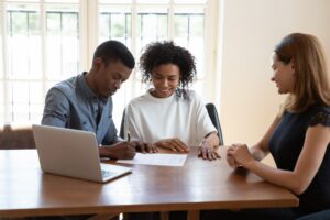 Happy young couple signs a document to finalize their agreement with a property manager.