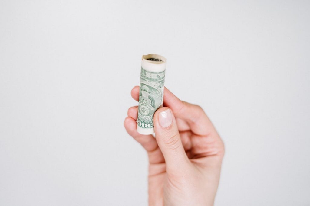 person holding up rolled up bill