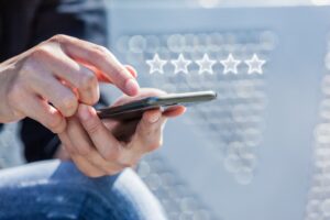 Close-up of person’s hand holding a smart phone with five star symbol.