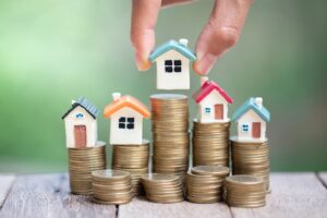 Tiny houses placed on stacks of coins representing increase in value