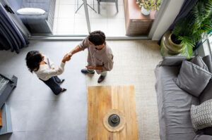High angle view of a landlord greeting a renter with a handshake at a rental home. 