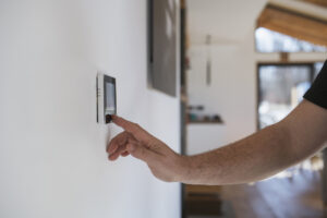 Man at home adjusting thermostat with device on the wall