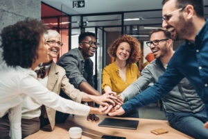 team getting motivated at the office with their hands over the table