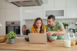 Happy couple at home viewing real estate online using their laptop computer.
