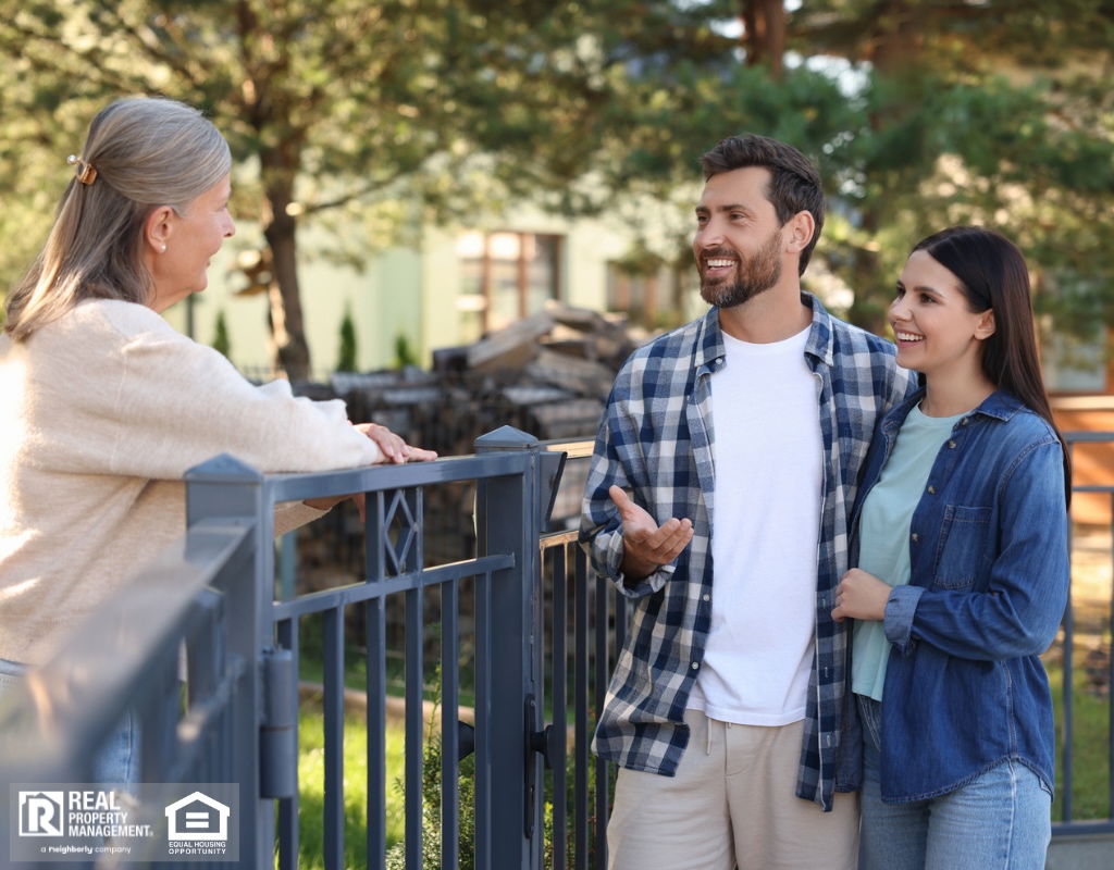Young couple talking to senior woman near fence outdoors.