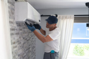 A man working on fixing an air conditioner inside a home. 