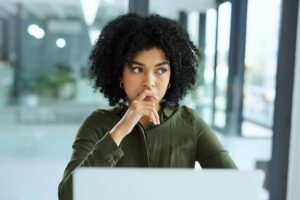 Businesswoman looking concerned while using a laptop in a modern office.