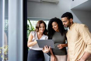 Happy group of people at a real estate showing looking at a digital tablet for details on a rental property.