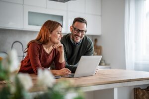 Happy couple at home viewing real estate online using their laptop computer.