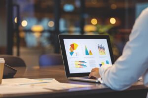 Real estate professional using a laptop with graphs and charts.