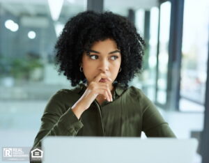 Businesswoman looking concerned while using a laptop in a modern office.