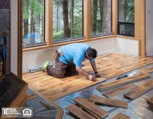 Man installing wood flooring in home.