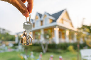 Hand holding keys to a beautiful new home.
