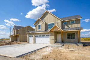 A partially built house with wooden framing and scaffolding, showcasing construction progress and tools on site.
