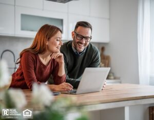 Happy couple at home viewing real estate online using their laptop computer.