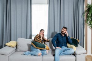 Young couple looking at the ceiling while concerned about noisiness from upstairs neighbor.