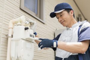 A worker checks on a gas meter outside a rental home.