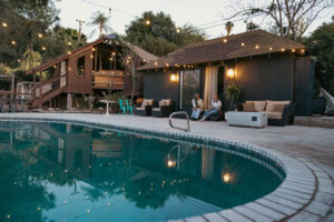 Two women enjoying a beautiful evening with a drink by the poolside of their rental house. 