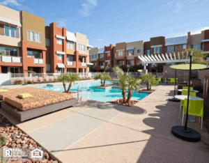 Outdoor pool and patio area at an apartment complex, featuring lounge chairs and greenery for relaxation.