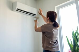 Woman turning on air conditioner.