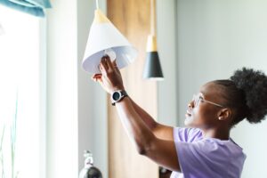 Young adult woman changing burnt out light bulb.