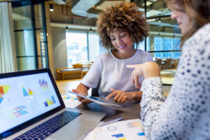 Business colleagues discussing finance charts and graphs on a laptop computer. 