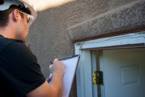 Inspector examining, taking notes and photographing an outdoor door jamb.