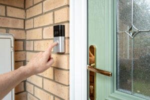 Visitor pressing the button of a wireless smart home door bell. 