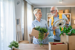 An older couple look overwhelmed as they pack up their home.
