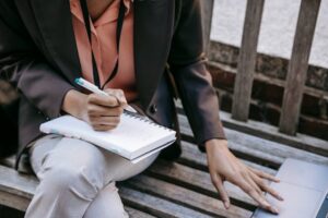 lady-on-bench-writing-in-book-and-on-laptop