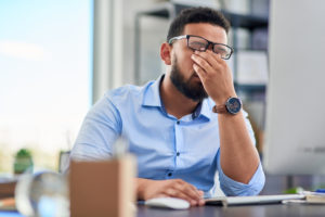 Young businessman sitting alone in his office appearing stressed