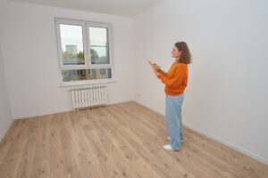 Woman inspecting empty apartment, making notes on a clipboard. 