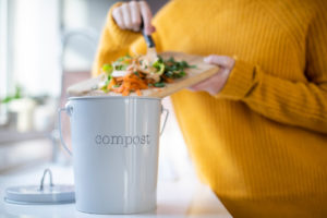 A Troy Renter Putting Veggies Scraps in a Compost Bucket