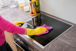 Person cleaning the stove in kitchen