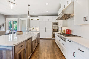 View of kitchen galley with hardwood flooring; brown and white colors throughout.