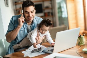 Remote Worker Holding His Baby While Working from Home