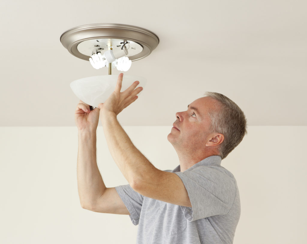 Redmond Property Manager Placing Energy Efficient Lightbulbs in a Fixture