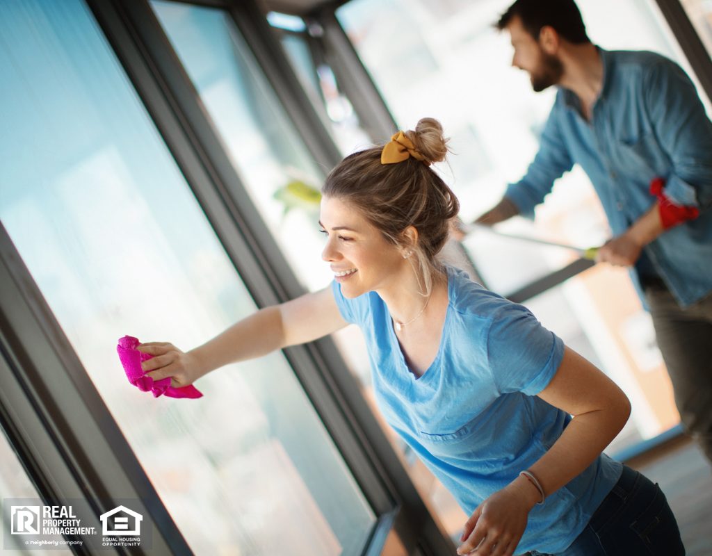 Couple Deep Cleaning Windows in Apartment