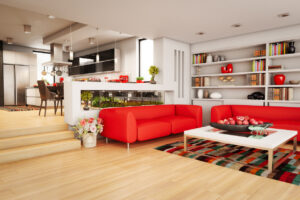 A modern living room featuring red furniture and an open kitchen area.
