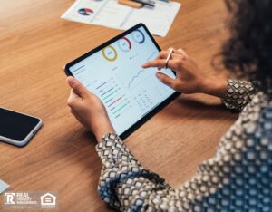 A woman using a tablet at her desk to check data on a business dashboard for rent collection.