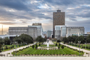 View of downtown Baton Rouge, Louisiana, showcasing the city’s skyline and lush gardens of the Capitol Grounds at sunset.